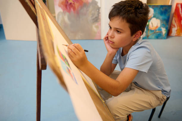 istock Young boy focusing on drawing during art class in a workshop 2156821744