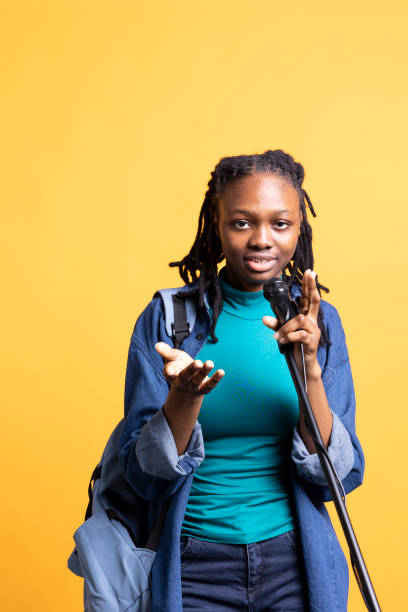 istock Woman holding microphone, performing songs in concert, studio background 2156825599