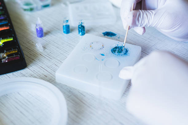 istock Children's hands in gloves fill an epoxy resin ring mold with decorative sparkles 2156825669