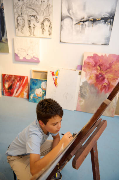 istock Young boy drawing in art class surrounded by inspirational artworks 2156825674