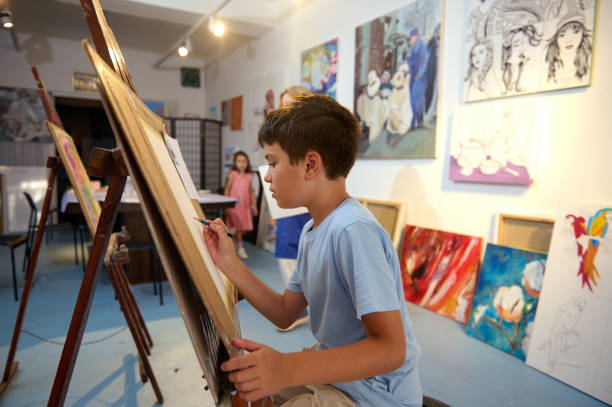 istock Children participating in art class, drawing and painting with a teacher in a creative workshop 2156829088