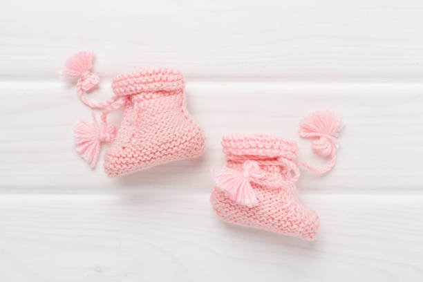 istock Pink baby booties on wooden background, top view 2156831350