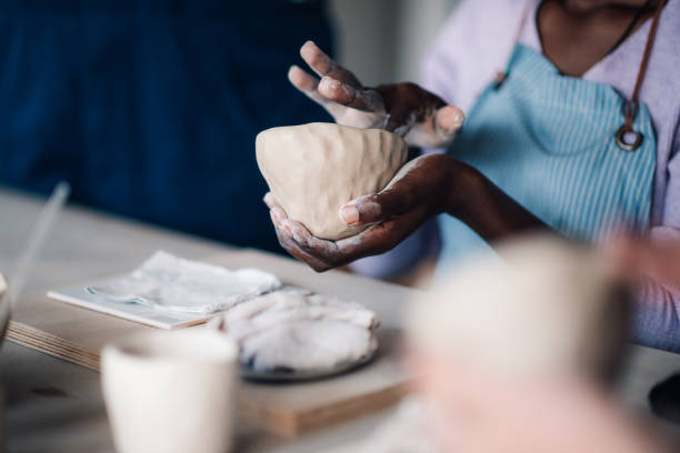 istock Close up of diverse pottery class student's hands shaping clay at studio 2156838239