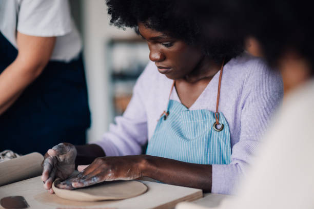 istock Portrait of diverse pottery class attendee sitting making clay plate. 2156838249