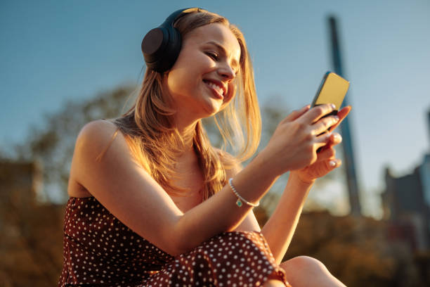 istock Woman laughing while using phone and headphones 2156838744