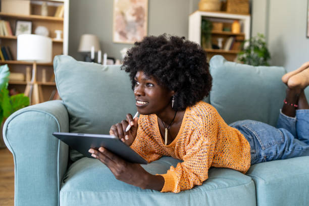 istock Cheerful young woman relaxing on a sofa while using a digital tablet at home 2156840192