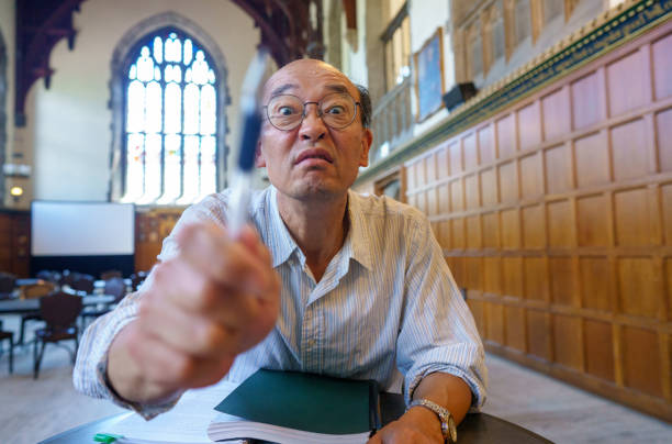 A male professor on the university campus, holding documents and looking very frustrated.
