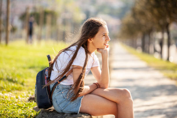 Pensive teen sitting in the par looking at view