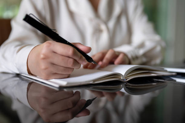 istock A cropped image of a businesswoman holding a pen, writing or taking notes in her notebook. 2156853162