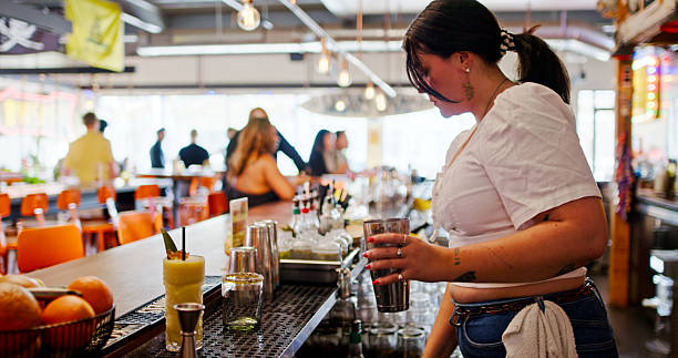 istock Female Bartender Prepares to Make a Drink with a Cocktail Shaker 2156859869