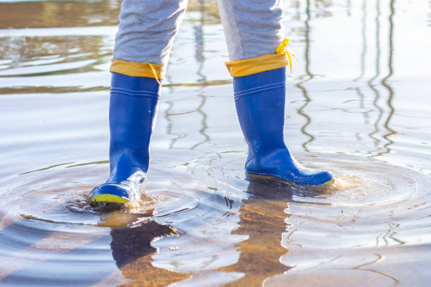 istock Child in blue galoshes playing in a flooded area 2156860588