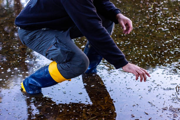 istock Man in rubber boots crouching in swampy area 2156860614