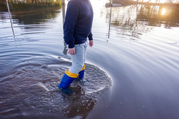 istock Boy protected with galoshes walking in flood zone 2156860615