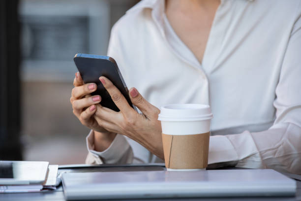 istock Mature woman checks email on smart phone while working from local cafe 2156864738