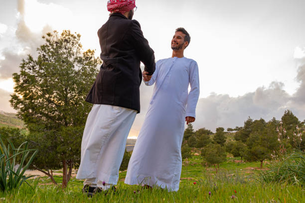 Two Arabic friends shaking hands in nature, having a wonderful time together during springtime in the wild, looking forward to collaborating together in the future