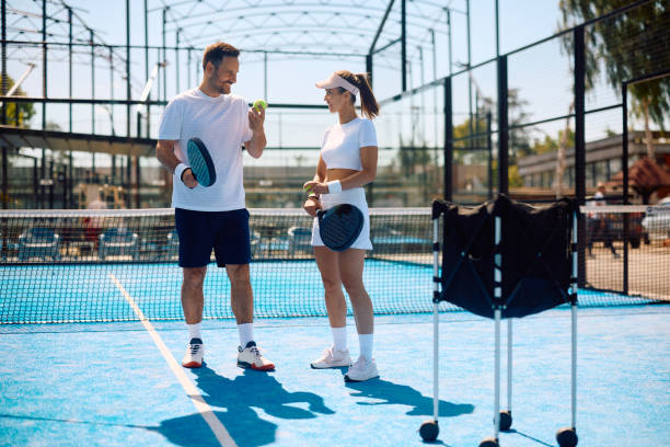 istock Happy athletic couple talking while playing paddle tennis on the court. 2156874384