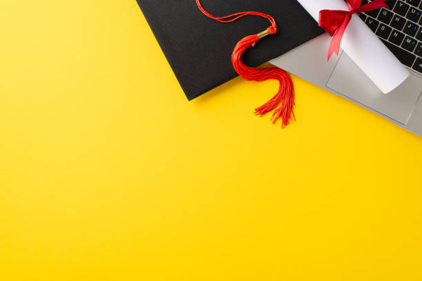 istock A vibrant image displaying a graduation cap with a red tassel resting on a laptop, set against a yellow background. Perfectly captures the essence of modern, virtual graduations 2156875213