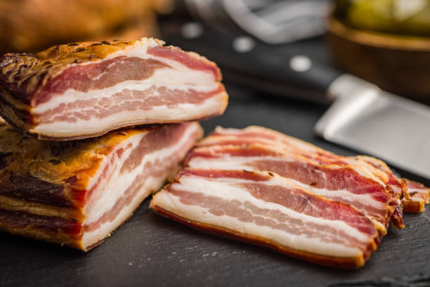 istock Closeup of Sliced Smoked Bacon on Black Slate Cutting Board 2156878843