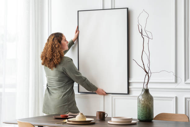 istock Woman hanging blank picture frame on the wall 2156879435