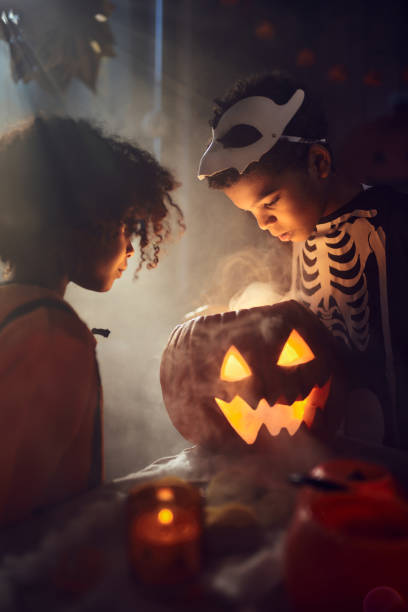 istock Little black siblings looking inside of Jack O' Lantern at home. 2156879540