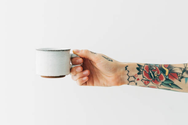 istock Tattooed hand holding a white coffee cup 2156880159