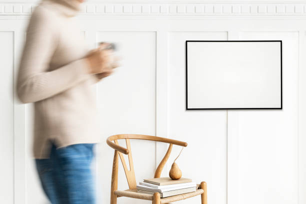 istock Woman walking past a black photo frame on a white wall mockup 2156881362