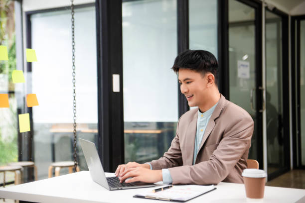 istock Young business man working at office with laptop, tablet and taking notes on the paper. 2156886876