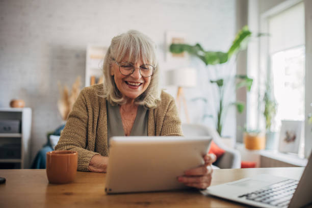 Senior white woman using a tablet and talking on video chat Senior white woman using a digital tablet and talking on video call old woman smiling tablet stock pictures, royalty-free photos & images