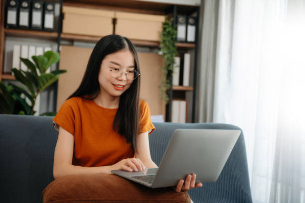 istock Asian woman using the smartphone and tablet on the sofa at home 2156888965