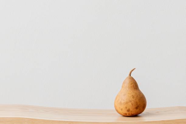 istock Brown pear on a wooden bench in a white room 2156889430
