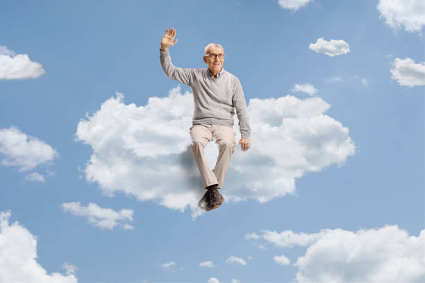 istock Cheerful elderly man sitting on a cloud and waving 2156889654