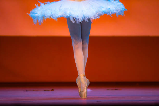 Girl performing contemporary dance on dark stage.