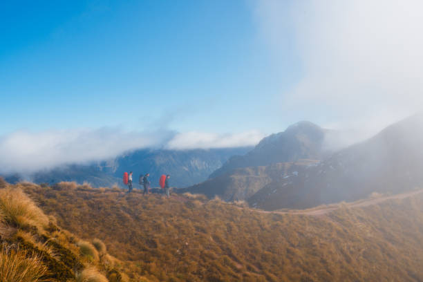 Hikers at top of tussock-covered ridgelines with spectacular alpine vista on Kepler track, South Island, New Zealand.