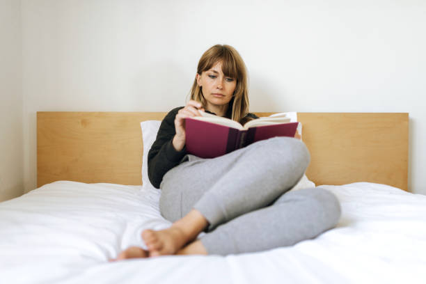 istock Woman reading a book on a bed during coronavirus quarantine 2156896288