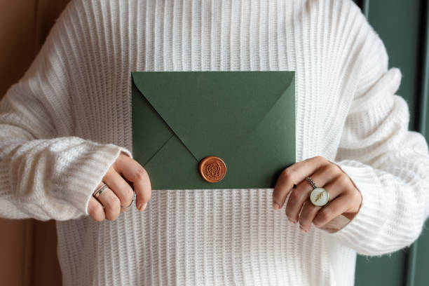 istock Woman in a white sweater holding a green envelope 2156896512