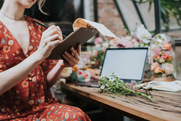 istock Florist sitting by her laptop writing on a notepad 2156898592