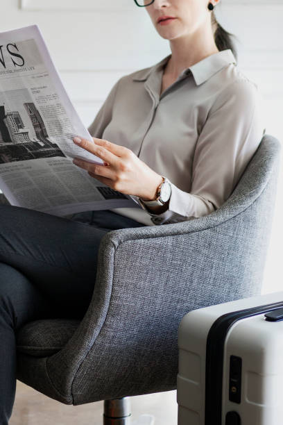 istock Businesswoman with a suitcase reading a newspaper 2156898741