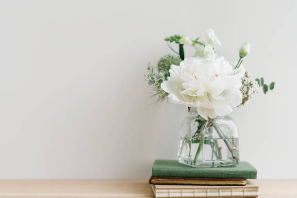 istock White flower bouquet in a cleared vase on a stack of books 2156900125