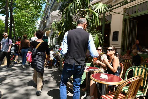 Paris, France-06 09 2024: Pedestrians, waiter and customers on the terrasse of a Parisian café, France.