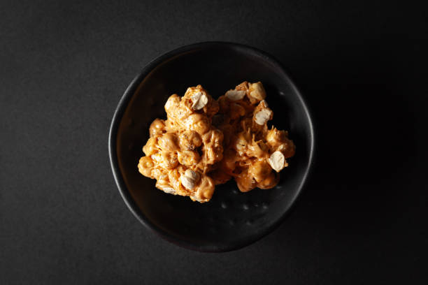 istock Two pieces of Chickpea (chana dal) chikki, placed in a black bowl on a black background. 2156903772