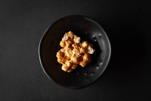 istock Two pieces of Chickpea (chana dal) chikki, placed in a black bowl on a black background. 2156903779