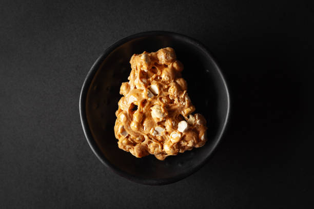 Two pieces of Chickpea (chana dal) chikki, placed in a black bowl on a black background.