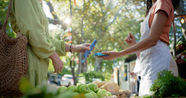 Groceries, hands and phone payment with people outdoor for agribusiness, commerce or retail. Contactless, NFC or fintech with customer and vendor at green market for organic produce or transaction compra de comestibles, manos y pago telefónico con personas al aire libre para agronegocios, comercio o venta al por menor. sin contacto, nfc o fintech con el cliente y el proveedor en el mercado verde para productos orgánicos o transacciones