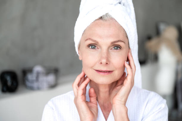 istock Middle age woman touching skin on face after applying moisturizer cream 2156908115