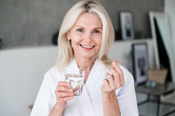 istock Smiling middle aged woman taking dietary supplement vitamin 2156908164