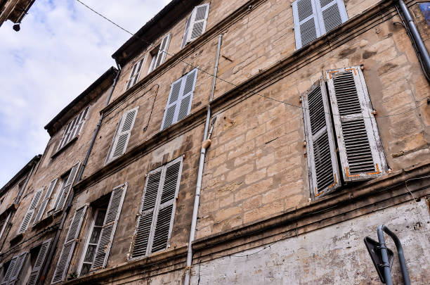 A building with many windows and a brick facade. The windows are open and the building appears to be old