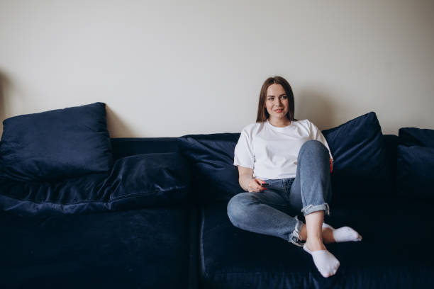 istock Young woman changing channels with remote control 2156913017