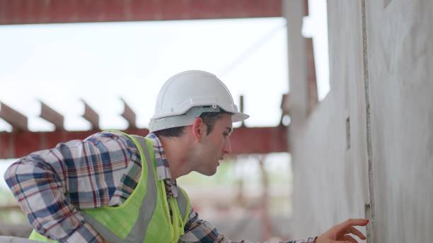 istock Engineer or contractors or architect wearing safety vest and haedhat working in construction site, building or housing project, check the construction progrss of the building or specifications and quality of the prefabricated walls in the production line 2156913589