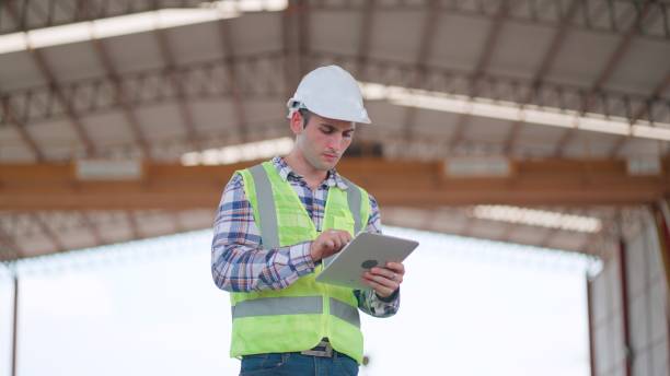 istock Industrial engineer use tablet check the construction progrss of the building or quality of product in the production line at factory. Contractors or architect with expertise and experience, wearing safety vest working in construction site. 2156913637