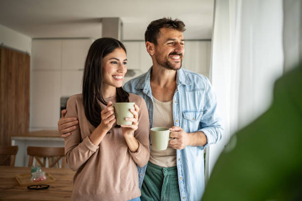 istock Young couple looking through the window in their home 2156914633